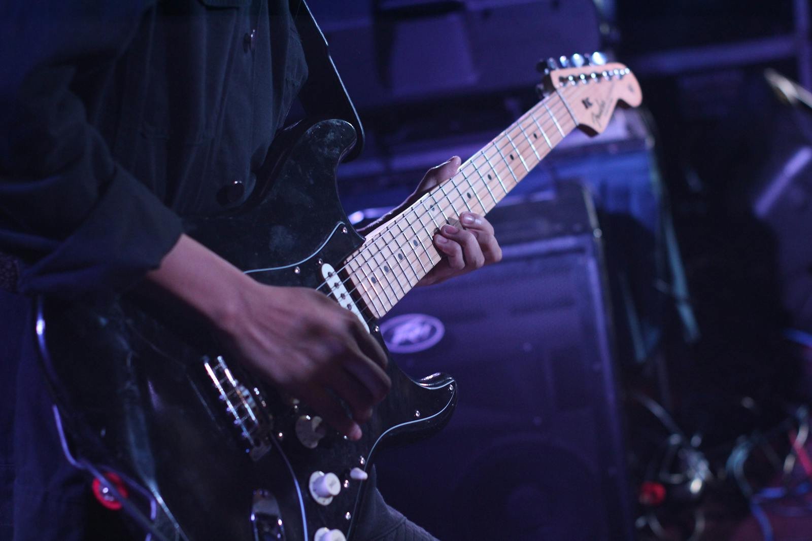 Musician playing an electric guitar on stage during a live performance.