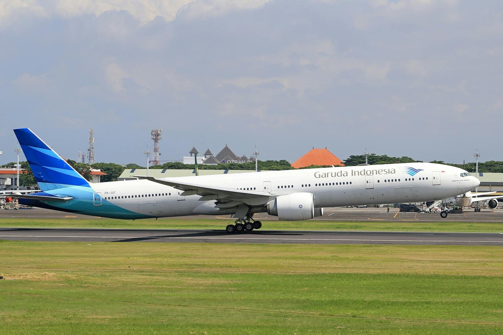 Garuda Indonesia airplane on the runway ready for takeoff under a clear sky.