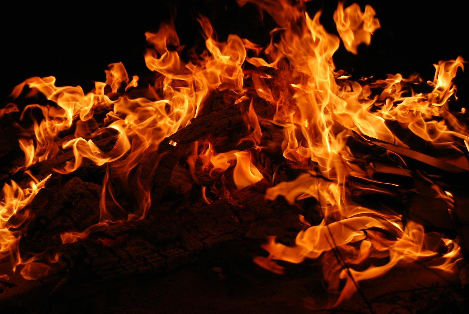 Close-up of a blazing bonfire with intense flames against a dark background.