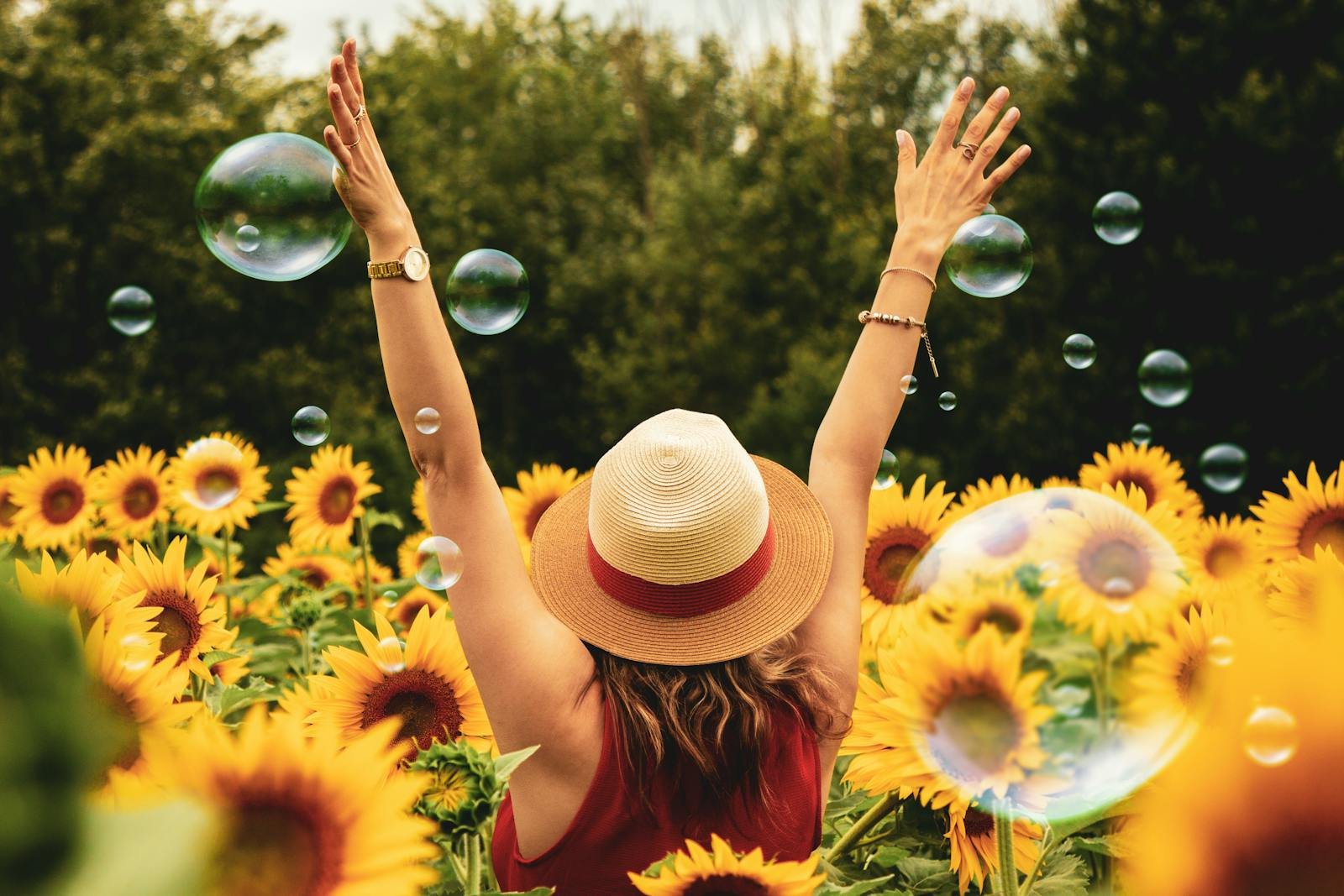 A joyful woman in a sunflower field with bubbles, expressing happiness on a summer day.