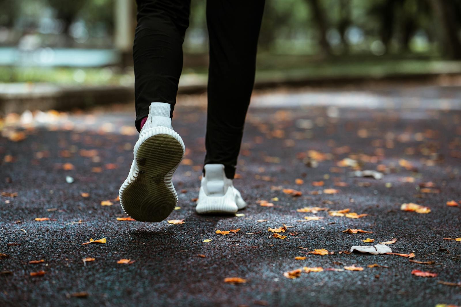 Legs of anonymous person in white sneakers and black leggings running on sidewalk