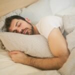 Man sleeping peacefully on striped bedding, embracing relaxation and comfort.